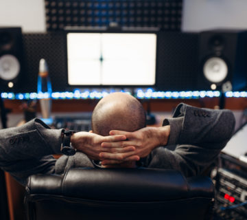 Male sound engineer at remote control, back view Male sound engineer at remote control panel, back view, recording studio. Musician at the mixer, professional audio mixing